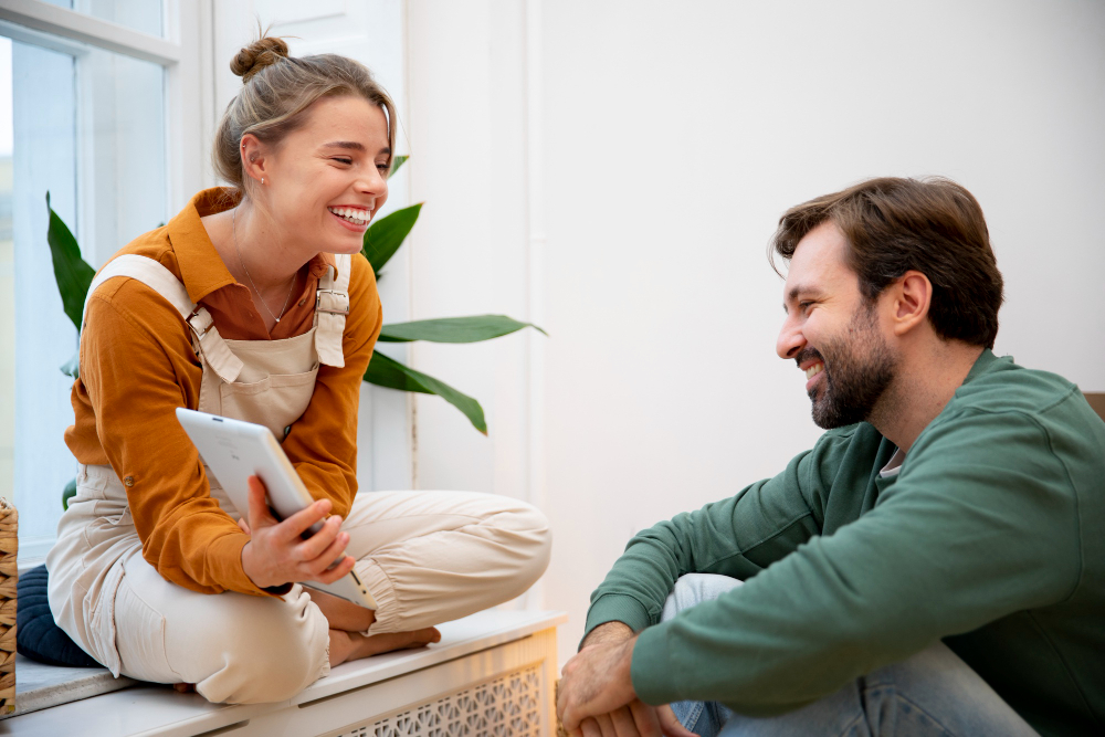 A loving couple sitting together, with the man attentively listening to the woman as she smiles, symbolizing the small yet meaningful ways men show their love through actions.