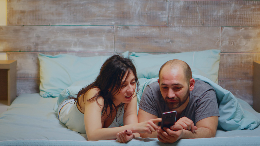 A cozy couple sharing a blanket and watching a movie together, capturing the warmth and intimacy of a first sleepover.